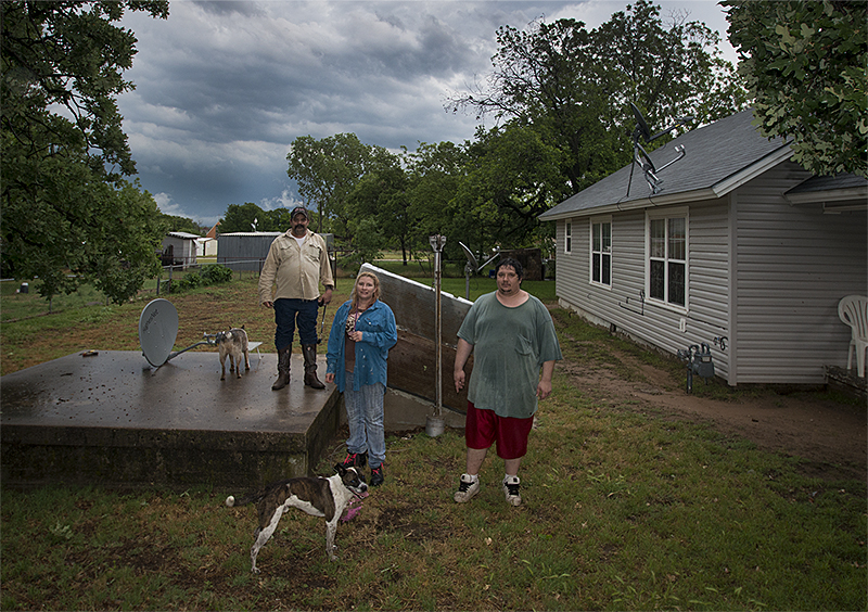 Dennis Mann, left, and his wife Deborah stand outside their storm cellar with neighbor Mathew Tettleton moments after a tornado warning ended on Monday May 20, 2013, in Montague, Texas. When I asked Deborah if they had gone to the cellar she laughed and said, "I did, but Dennis stayed out here to make sure his truck didn't blow away."  ©2013 Robert W. Hart